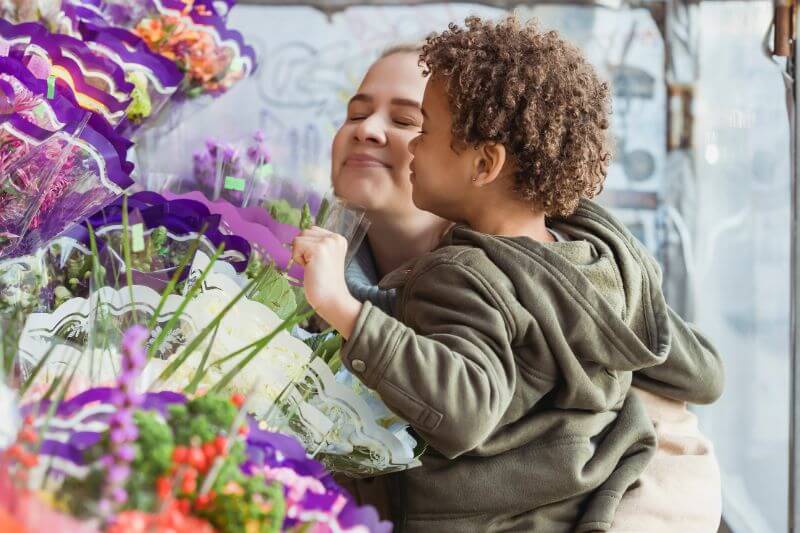 Mom and child smelling flowers.